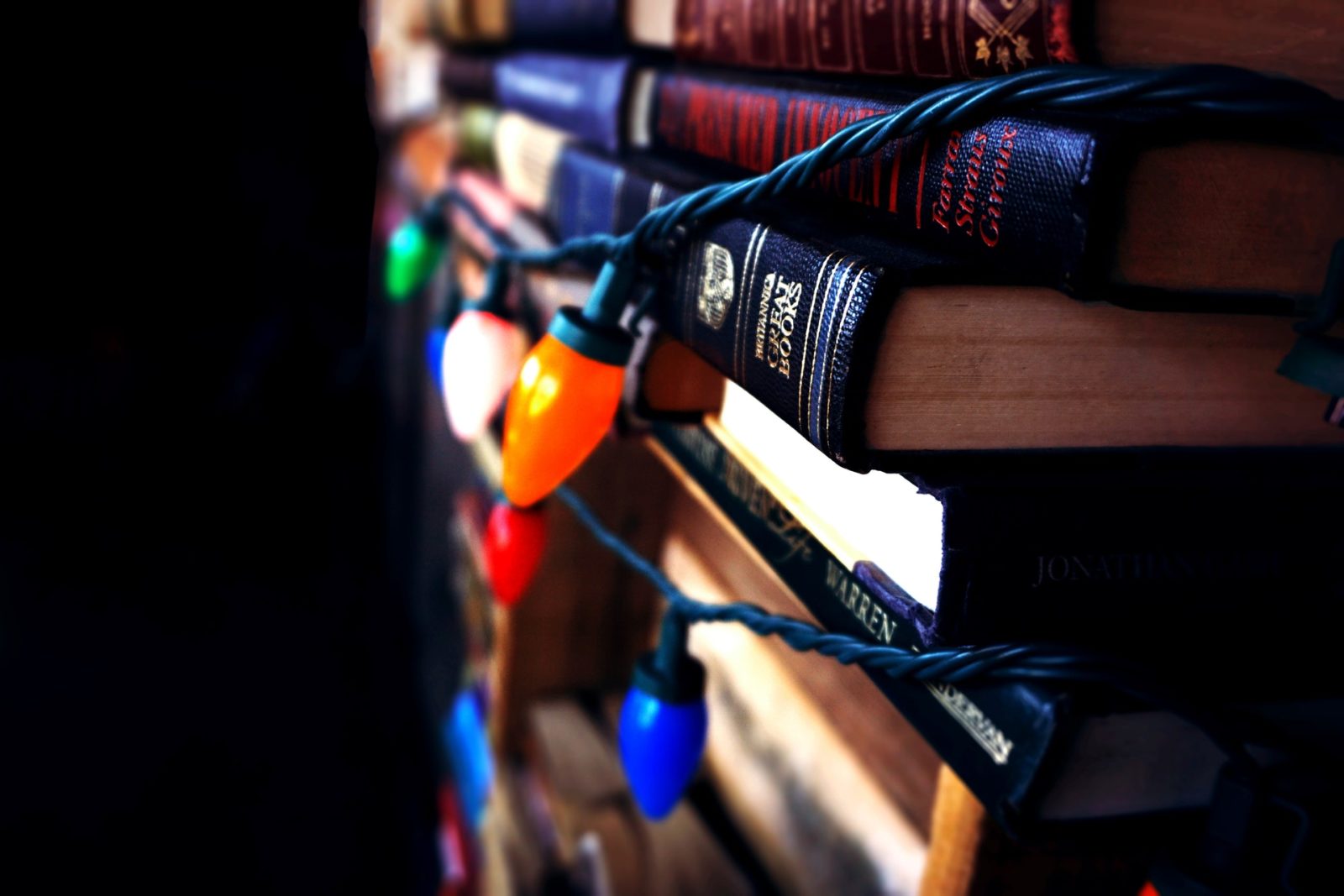 books stacked and draped in christmas lights